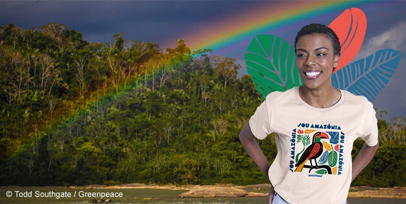 mulher negra cabelos curtos vestindo a camiseta da campanha com uma imagem da floresta preservada e um arco-iris